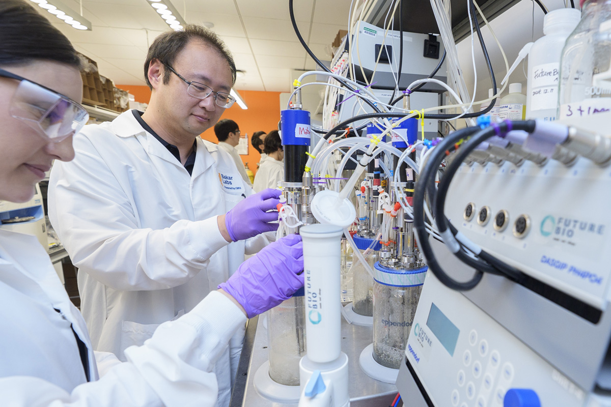 Two people in lab coats work at a biofermenting station